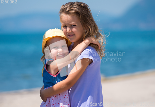 Image of little sisters hugging on the beach coast