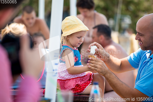 Image of cute little girl eating ice cream with her young father