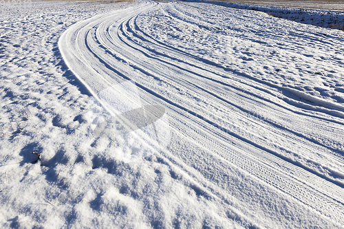 Image of snow-covered road in a field