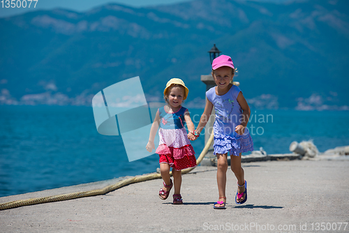 Image of little sisters running on the beach coast