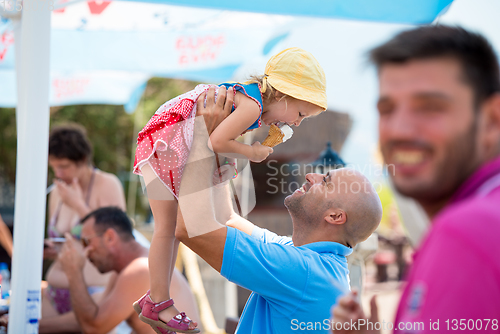 Image of cute little girl eating ice cream with her young father