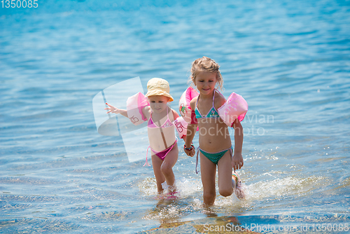 Image of little girls with swimming armbands playing in shallow water