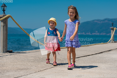 Image of little sisters walking on the beach coast