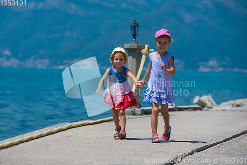Image of little sisters running on the beach coast