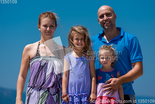 Image of portrait of young happy family with daughters by the sea
