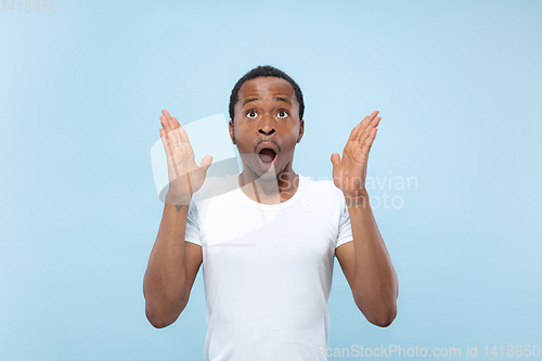 Image of Half-length close up portrait of young man on blue background.