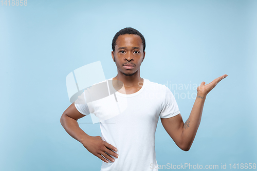 Image of Half-length close up portrait of young man on blue background.