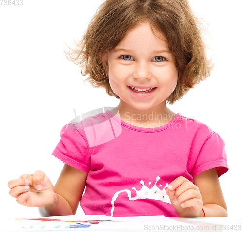 Image of Little girl is painting with gouache