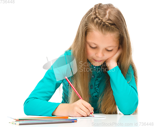 Image of Little girl is drawing using pencils