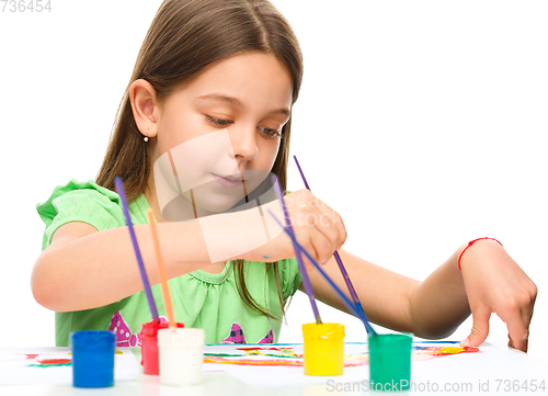 Image of Little girl is painting with gouache