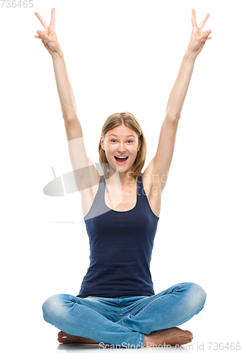 Image of Young happy woman is sitting on the floor