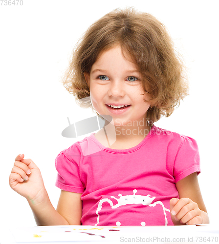 Image of Little girl is painting with gouache