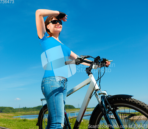 Image of Young woman is standing in front of her bicycle