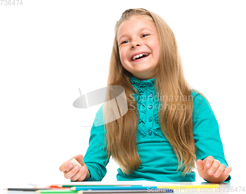 Image of Little girl is drawing using pencils