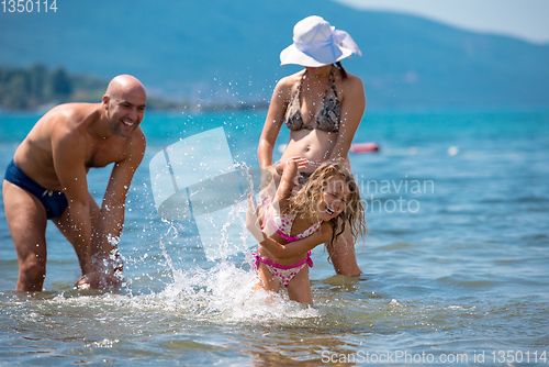 Image of happy family splashing each other at beach