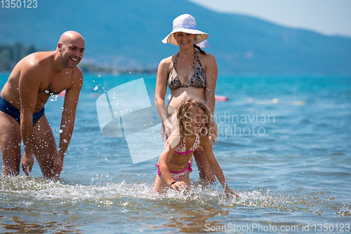 Image of happy family splashing each other at beach