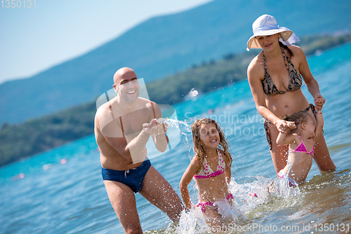 Image of happy family splashing each other at beach