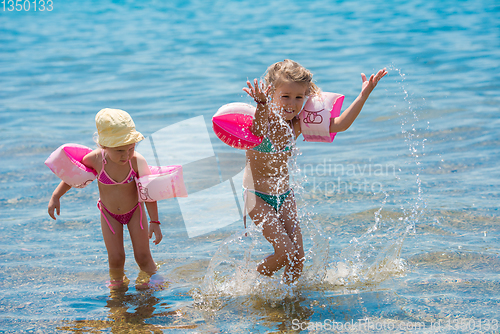 Image of little girls with swimming armbands playing in shallow water