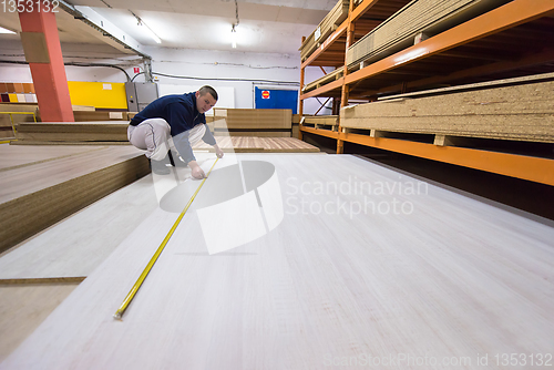 Image of carpenter measuring wooden board