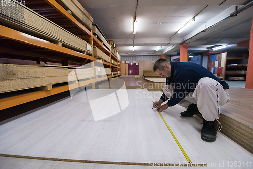 Image of carpenter measuring wooden board