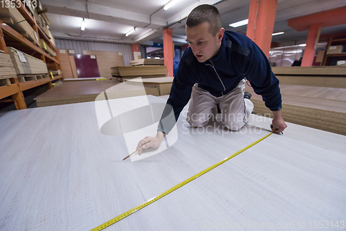 Image of carpenter measuring wooden board