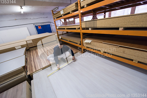 Image of carpenter measuring wooden board