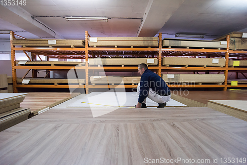 Image of carpenter measuring wooden board
