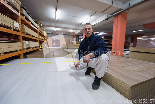 Image of carpenter measuring wooden board