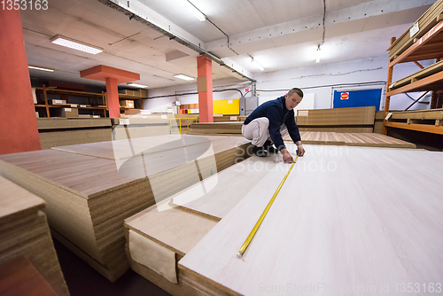 Image of carpenter measuring wooden board