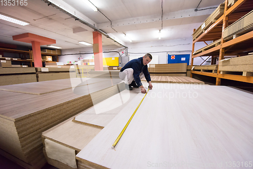 Image of carpenter measuring wooden board