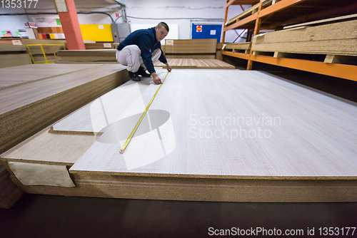 Image of carpenter measuring wooden board