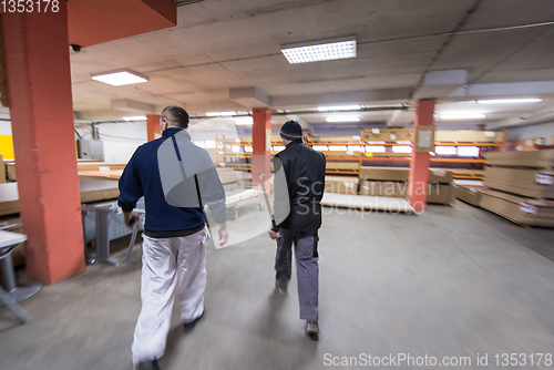 Image of two young carpenters working in big modern carpentry