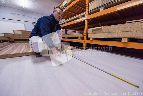 Image of carpenter measuring wooden board