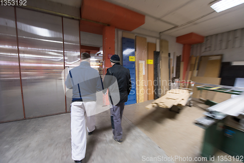 Image of two young carpenters working in big modern carpentry