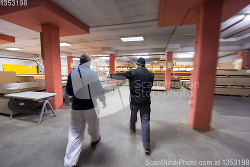 Image of two young carpenters working in big modern carpentry