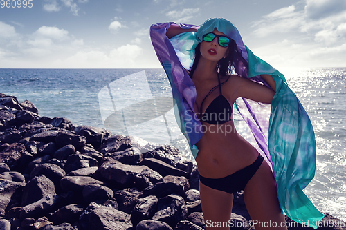 Image of beautiful girl standing on rocky shore