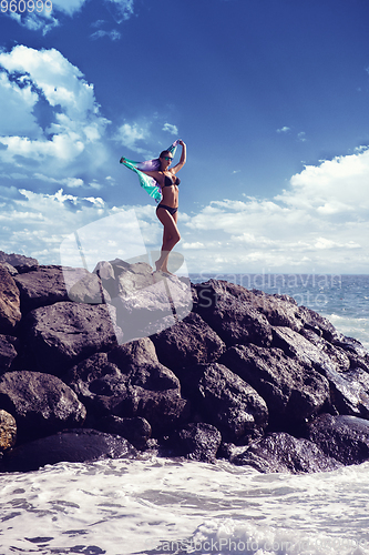 Image of beautiful girl standing on rocky shore