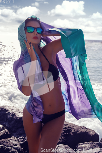 Image of beautiful girl standing on rocky shore