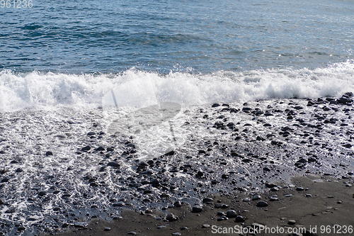 Image of ocean water on black sand