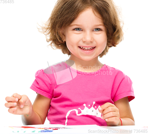 Image of Little girl is painting with gouache