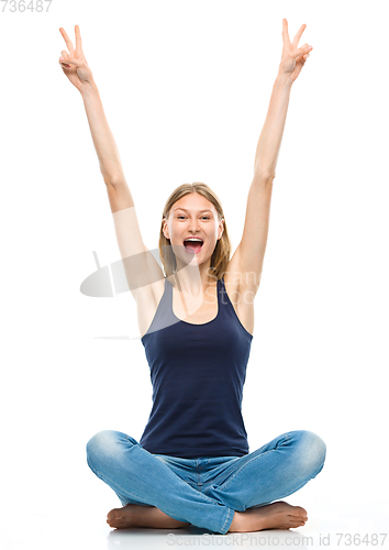 Image of Young happy woman is sitting on the floor