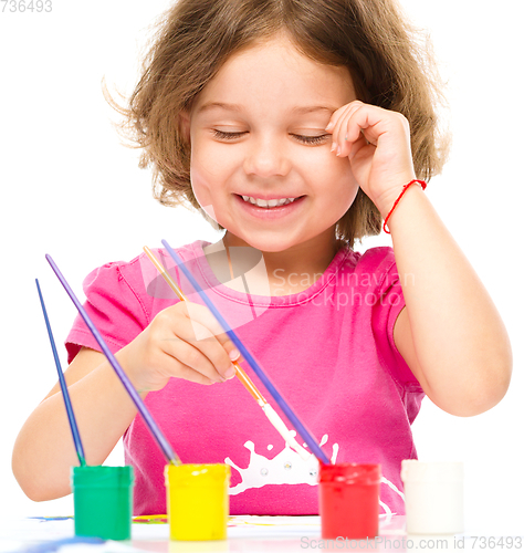 Image of Little girl is painting with gouache