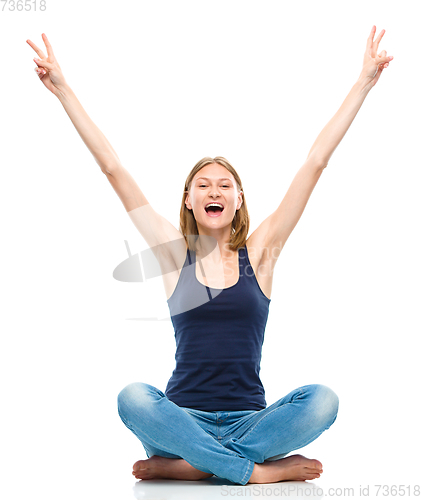 Image of Young happy woman is sitting on the floor