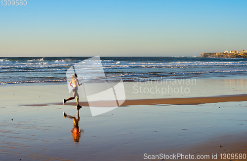 Image of Woman running ocean beach sunset