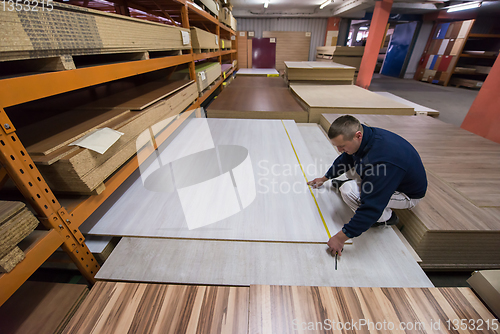 Image of carpenter measuring wooden board