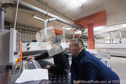 Image of carpenters calculating and programming a cnc wood working machin