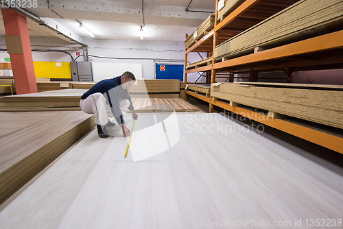 Image of carpenter measuring wooden board