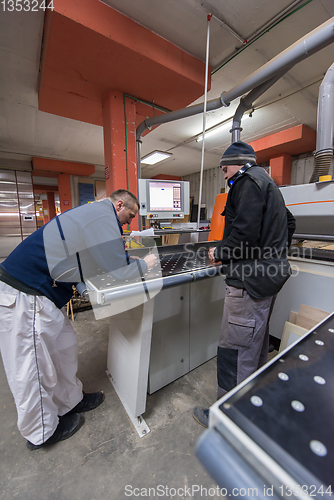 Image of carpenters calculating and programming a cnc wood working machin