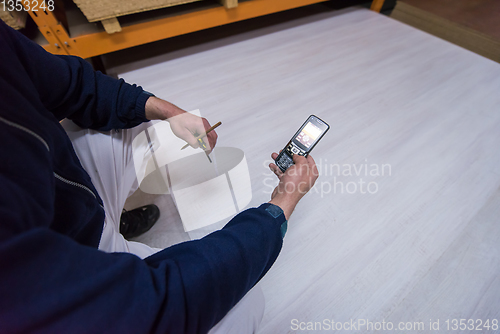 Image of carpenter using a mobile phone to calculate measures