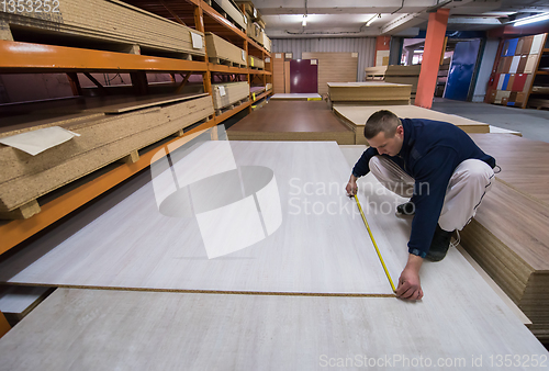 Image of carpenter measuring wooden board